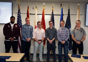 Group of people in front of flags.